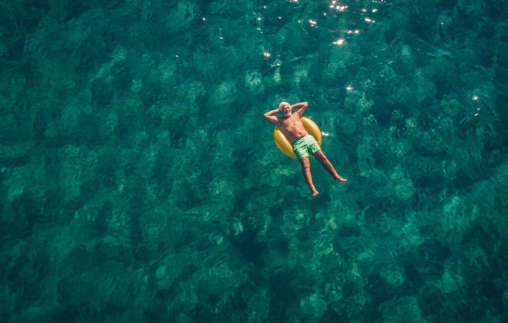 Thrive Program. Man relaxing, floating on an inflatable ring in calm seas